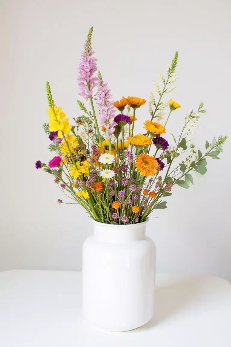 Classic Wildflower Centerpiece A photo of a white vase filled with colorful wildflowers