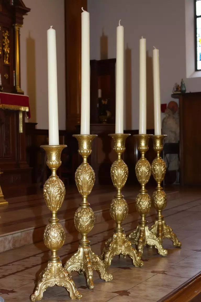 Antique Candlestick Church Decorations A photo of six tall, antique candlesticks with ornate designs arranged at the front of a church