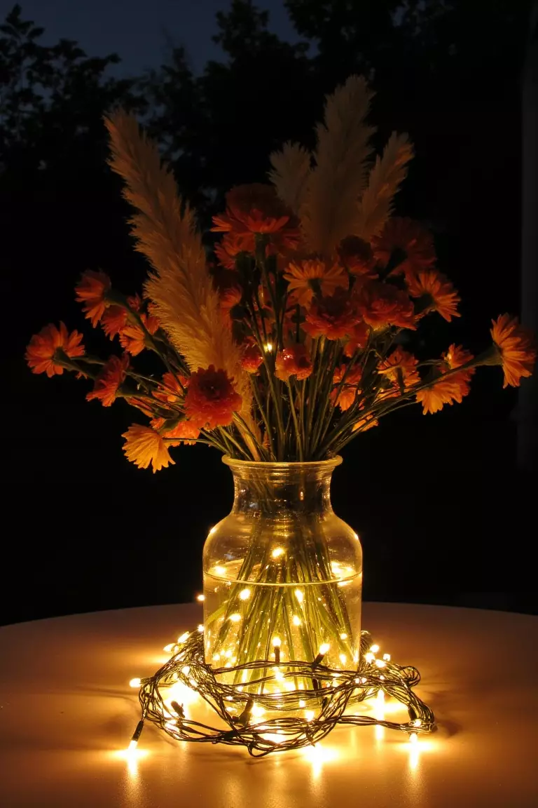 Whimsical Fairy Lights A photo of wildflowers arranged in a glass vase intertwined with fairy lights, casting a warm glow during an evening gathering.