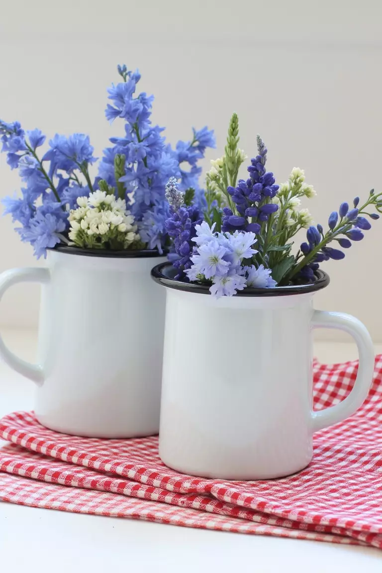 Whimsical Wonderland Wildflower Centerpiece A photo of enamel milk cans with delphiniums, scabiosa, and larkspur on checkered cloths