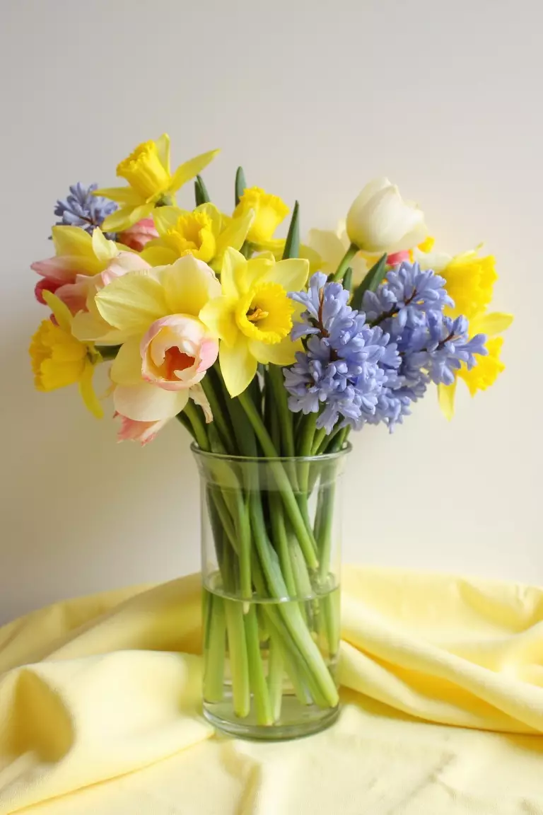 Spring Sensation Wildflower Centerpiece A photo of tulips, daffodils, and hyacinths in a clear vase on pale yellow linens