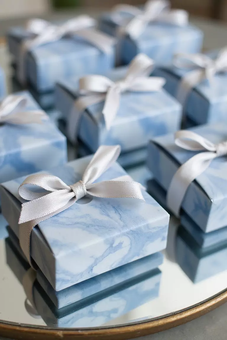 Blue And White Marbled Wedding Favors A professional photo, similar to a photo in a wedding magazine, of artisanal blue and white marbled wedding favor boxes tied with silver ribbon arranged on a mirrored display.