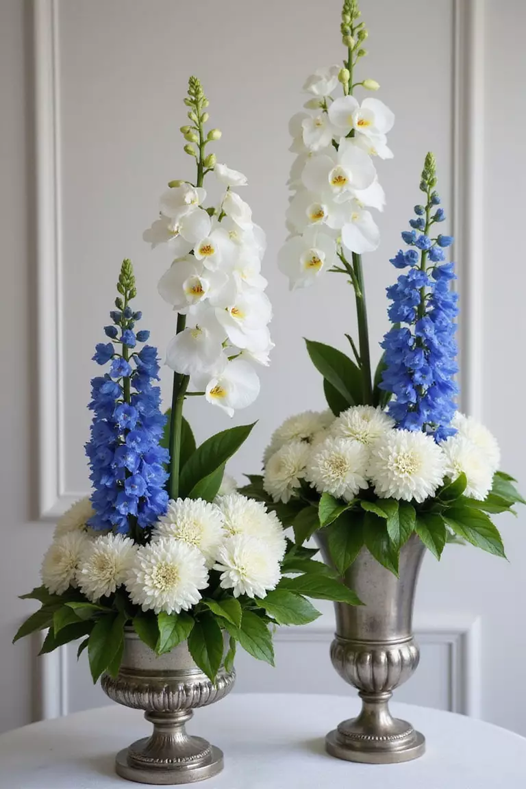 White Orchid And Blue Delphinium Arrangements A professional photo, similar to a photo in a wedding magazine, of sophisticated floral arrangements combining white orchids and tall blue delphiniums in silver urns.