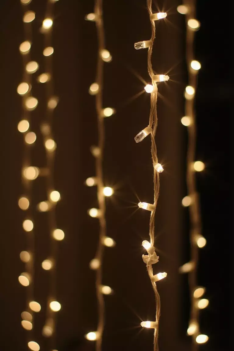 Fairy Light Curtain A professional photo, similar to a photo in a wedding magazine, of strands of warm white fairy lights hanging vertically like a curtain against a dark background, creating a bokeh effect.
