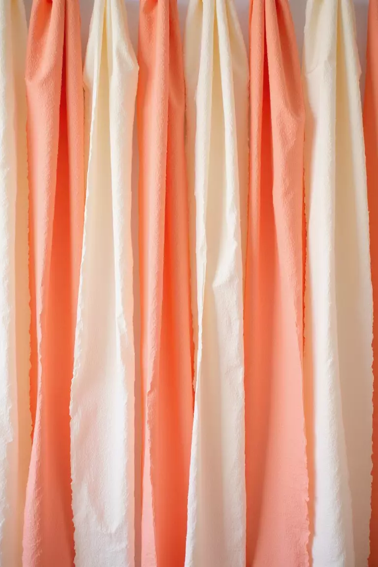 Streamer Wall A professional photo, similar to a photo in a wedding magazine, of crepe paper streamers in peach, coral, and cream hanging vertically, slightly twisted, creating a textured backdrop.