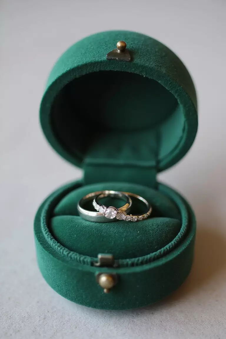Velvet Ring Box A professional photo, similar to a photo in a wedding magazine, of two wedding rings nestled inside a small, plush emerald green velvet ring box with hinged lid.