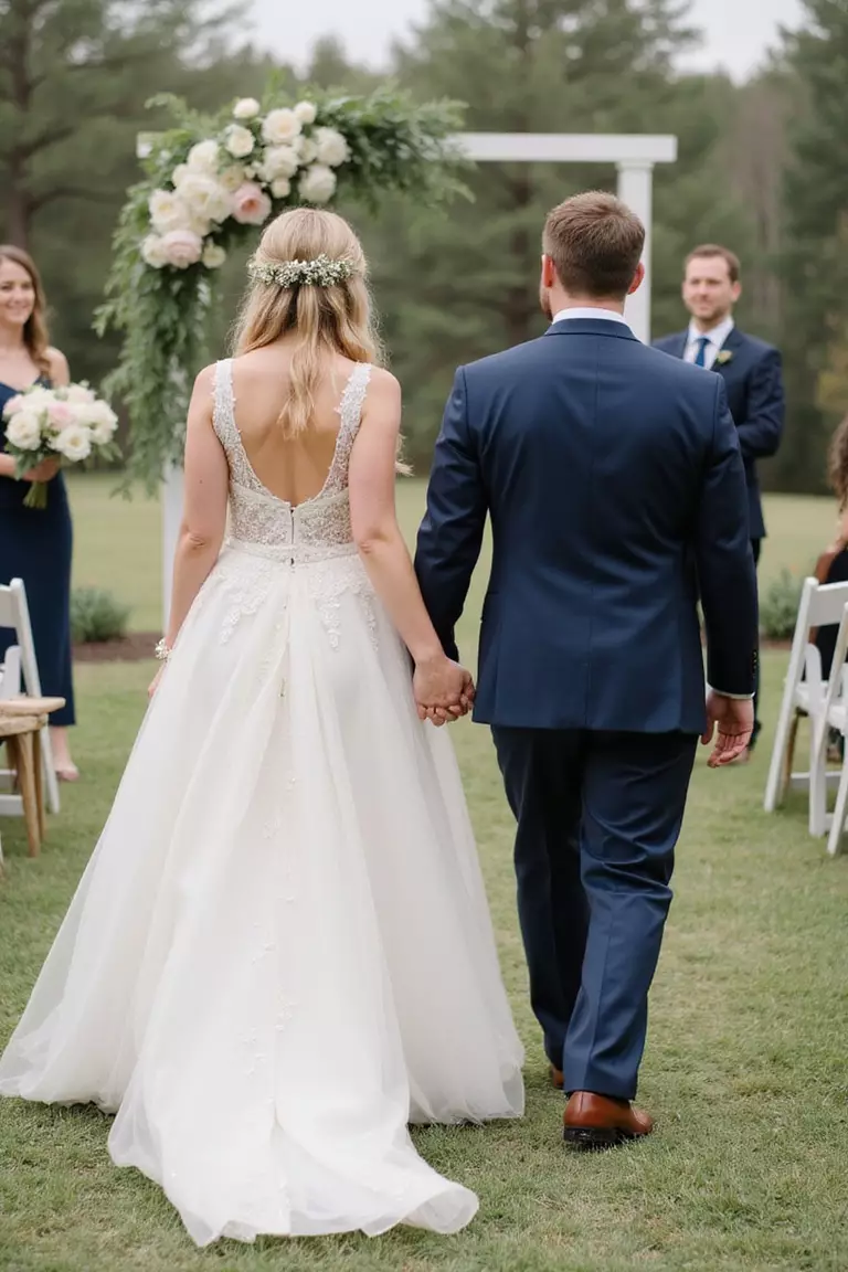 Keep The Ceremony Short A professional photo, similar to a photo in a wedding magazine, of a smiling couple walking back down the aisle holding hands after a brief outdoor wedding ceremony.