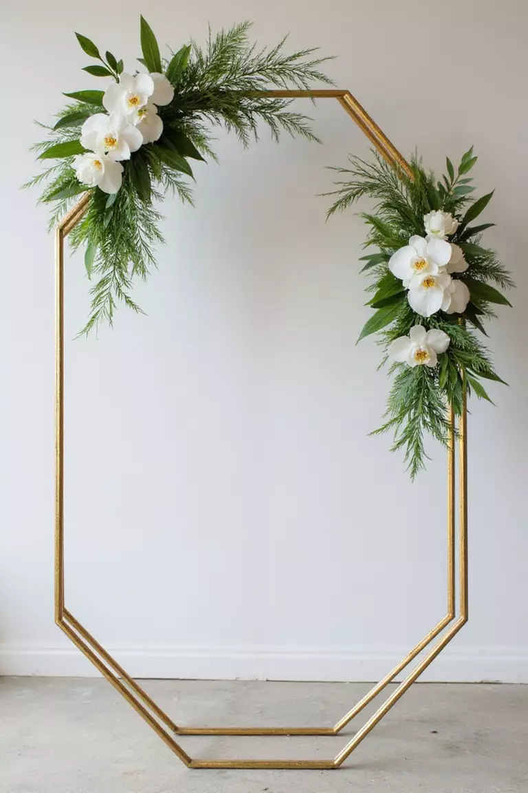 Geometric Frame With Florals A professional photo, similar to a photo in a wedding magazine, of a large gold hexagonal metal frame decorated with asymmetrical arrangements of white orchids and green foliage.