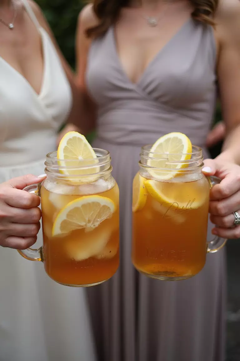 Mason Jar Drinks A professional photo, similar to a photo in a wedding magazine, of guests holding mason jars filled with iced tea and lemonade, garnished with lemon slices.