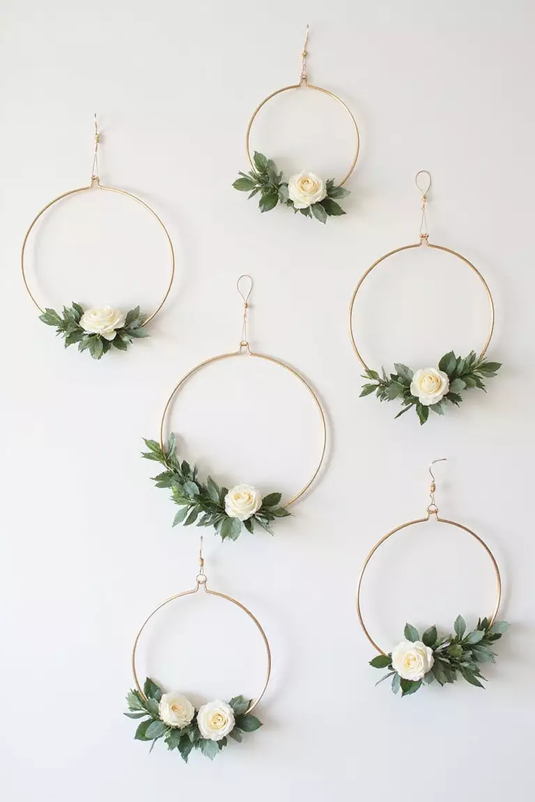 Hanging Floral Hoops A professional photo, similar to a photo in a wedding magazine, of several gold metal hoops decorated with eucalyptus and white roses hanging at different heights against a plain white wall.