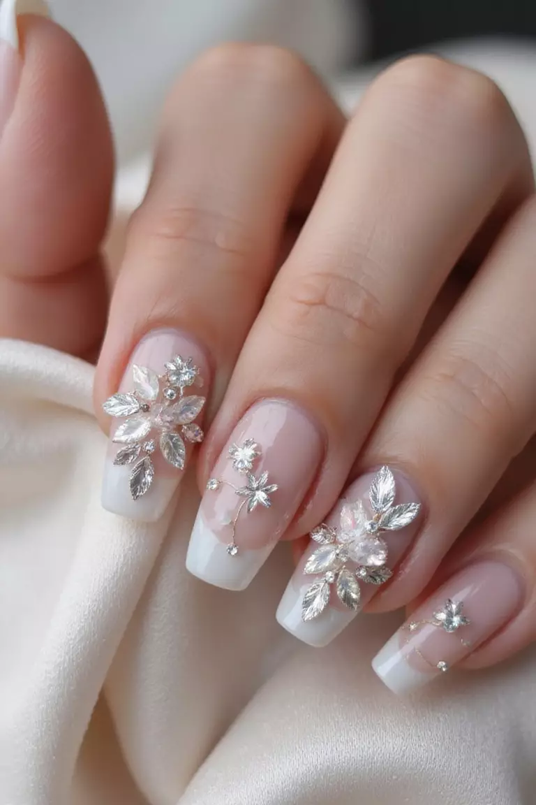 Acrylic Artistry: Sculptural Beauty for the Statement Bride Close-up of a woman's hand with sculpted acrylic nails featuring 3D flower elements, crystal embellishments, and pearlescent finish against a luxurious satin background.