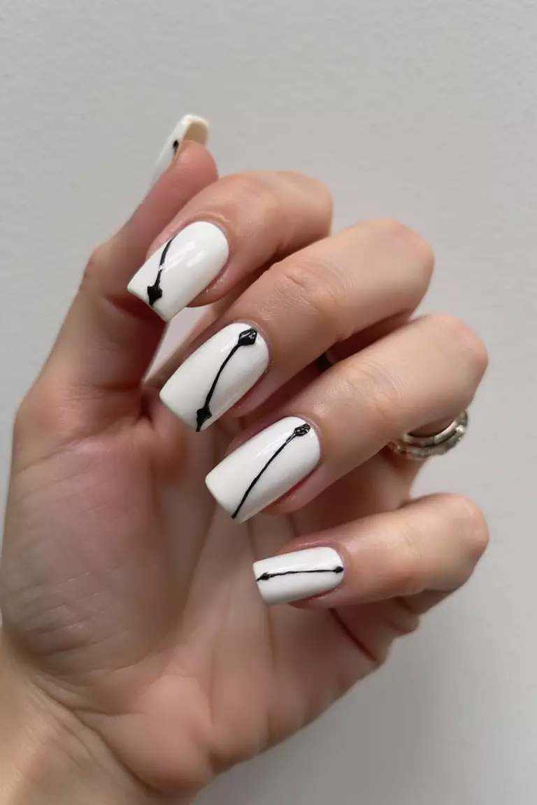 Black and White Wedding Nails Close-up of a woman's hand with five fingers featuring white nails with elegant black accents, creating a sophisticated contrast against a neutral background.