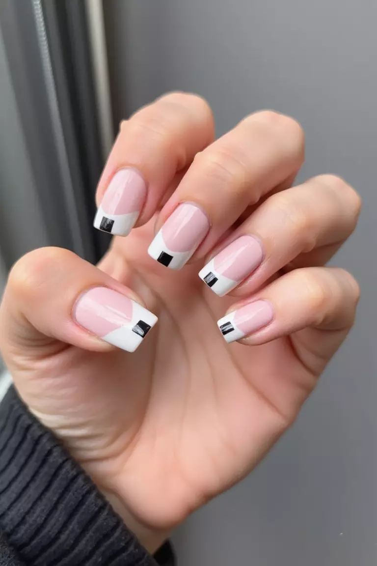 Modern French: Updated Classics for the Contemporary Bride Close-up of a woman's hand with modern French manicure featuring non-traditional colored tips in pale pink, geometric shapes, and negative space against a sleek background.