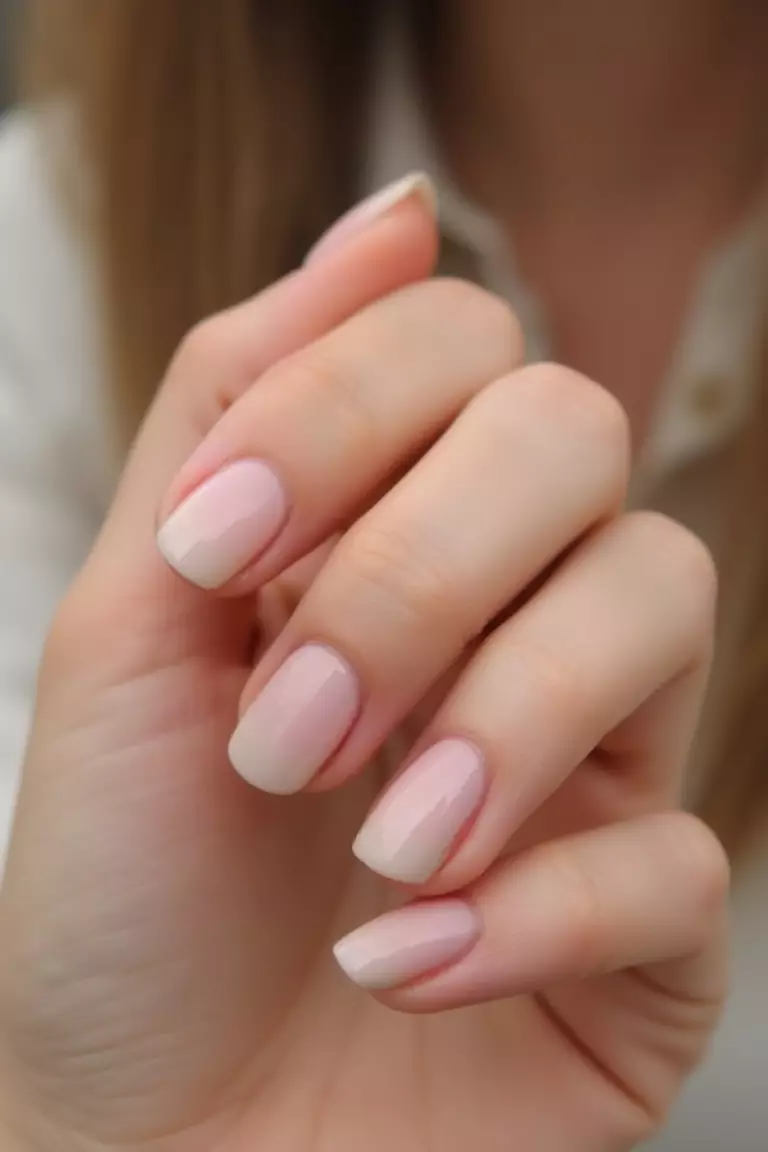 Subtle Ombré Close-up of a woman's hand with nails featuring a subtle ombré effect from nude to light pink.