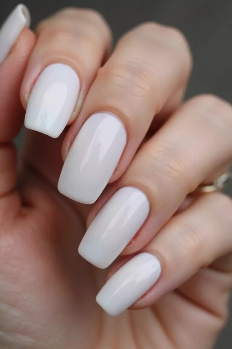 Sheer Glazed Doughnut Nails Close-up of a woman's hand with five fingers featuring white sheer nails with a glossy, reflective finish that looks wet and dewy.