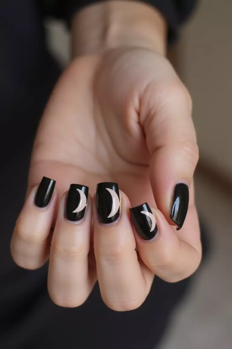 Black with Nude Accents Close-up of a woman's hand with five fingers featuring black nails with nude geometric shapes or half-moon designs creating elegant contrast.