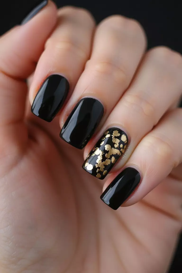 Black with Gold Foil Close-up of a woman's hand with five fingers featuring black nails with irregular gold foil accents scattered across, creating luxurious contrast.