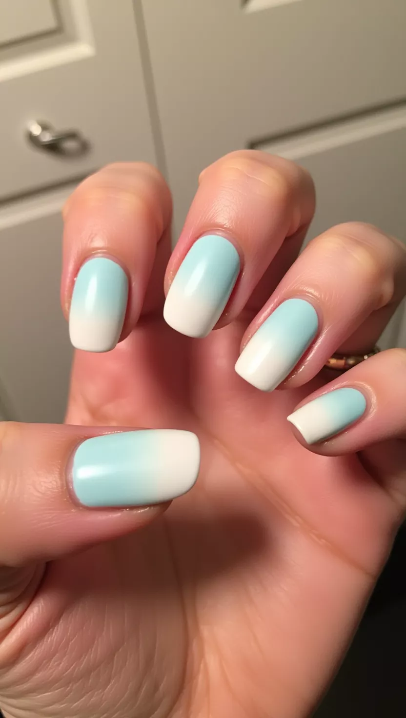 Matte Powder Blue Fade close-up photo of a woman’s hand with five fingers showing nails with a soft powder blue to white ombre fade finished with a completely matte top coat, room background