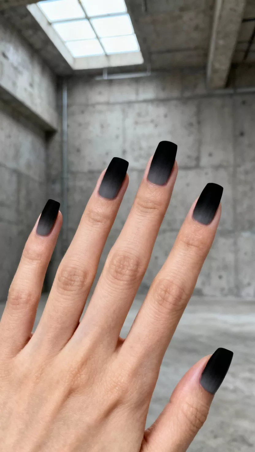 close-up shot of a woman’s hand with five fingers showing nails with a seamless gradient transition from a dark charcoal gray at the cuticle fading into a solid jet black tip, concrete urban loft background.