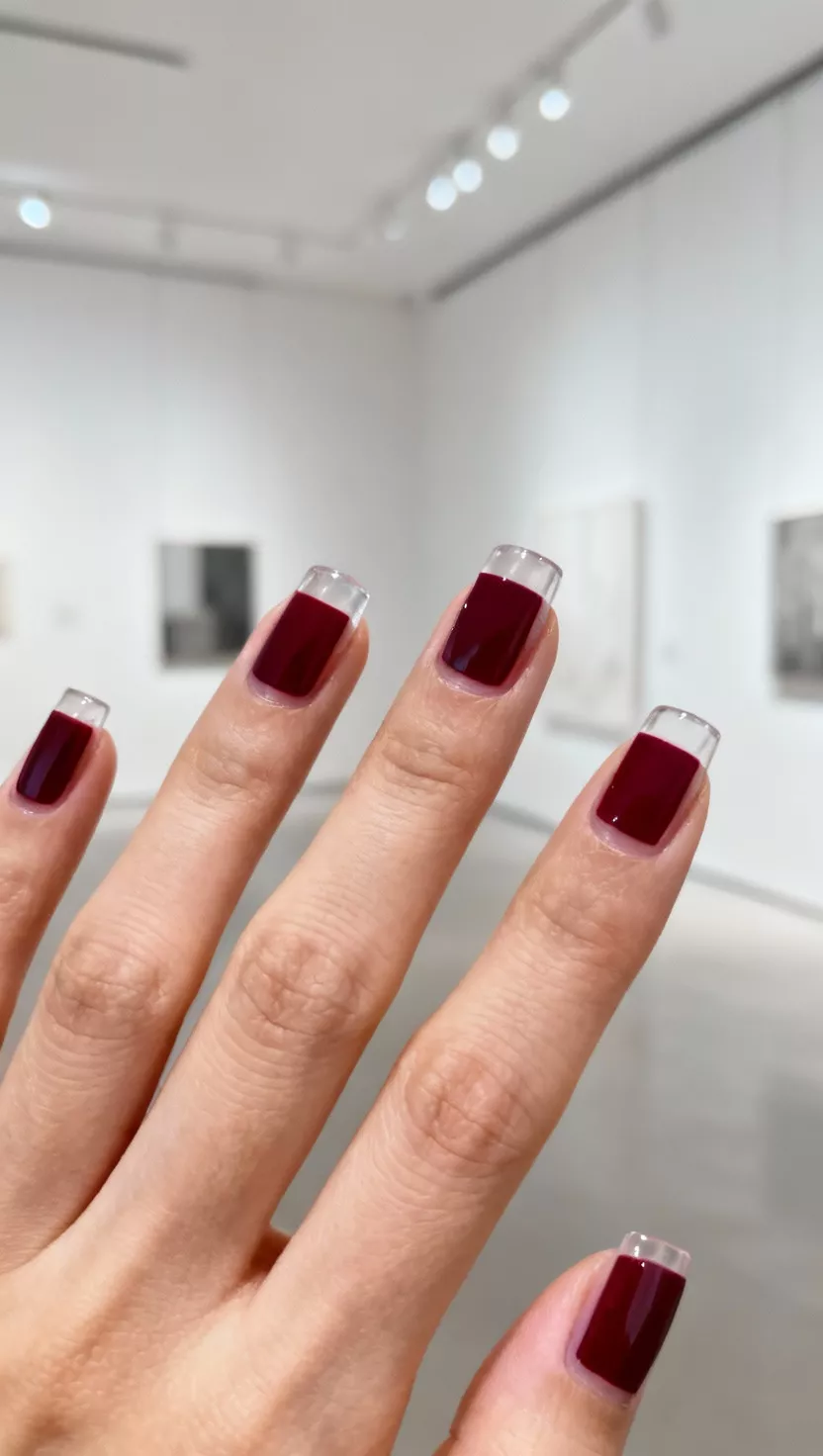 Negative Space Design with a Single Color Block close-up shot of a woman’s hand with five fingers showing nails with a clear base coat featuring a single, precise rectangular block of deep wine red polish creating a negative space effect, modern gallery background.