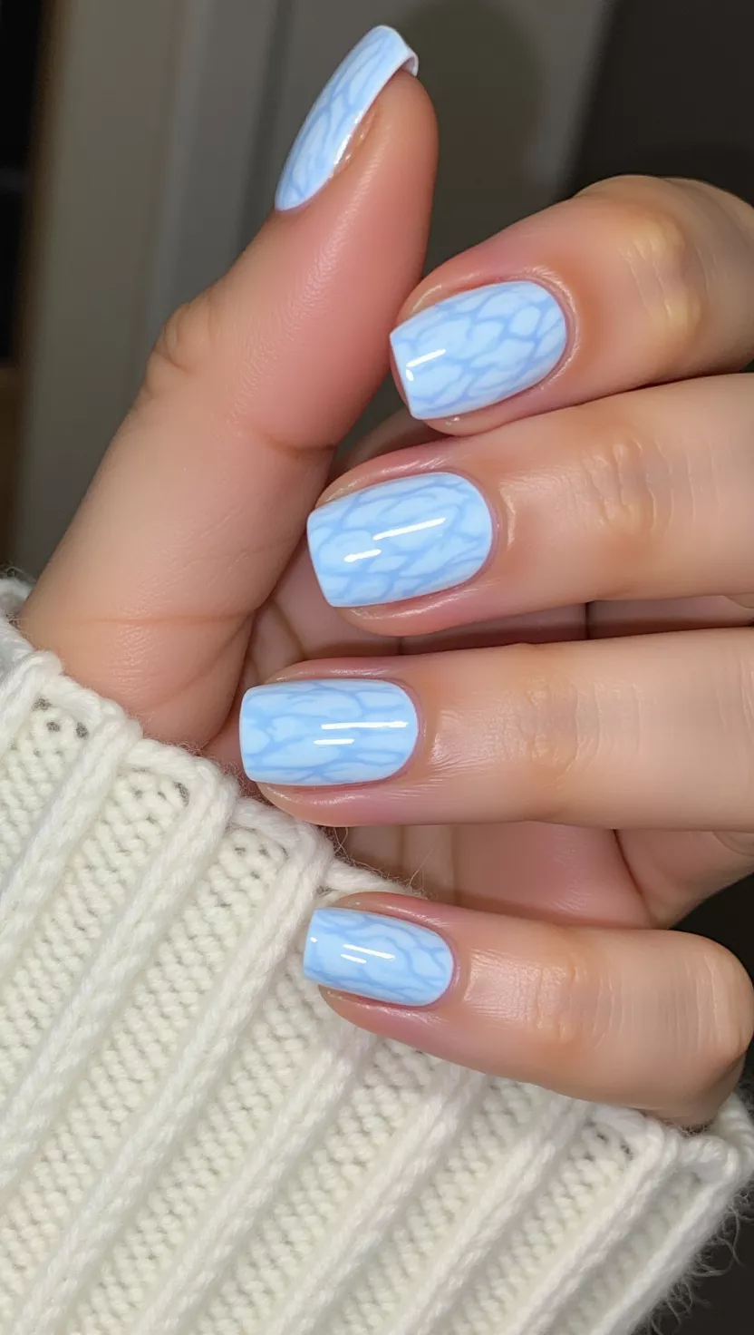 Light Blue Sweater Texture close-up photo of a woman’s hand with five fingers showing nails with light, pastel blue nails featuring a raised, cable-knit sweater texture using 3D gel, room background