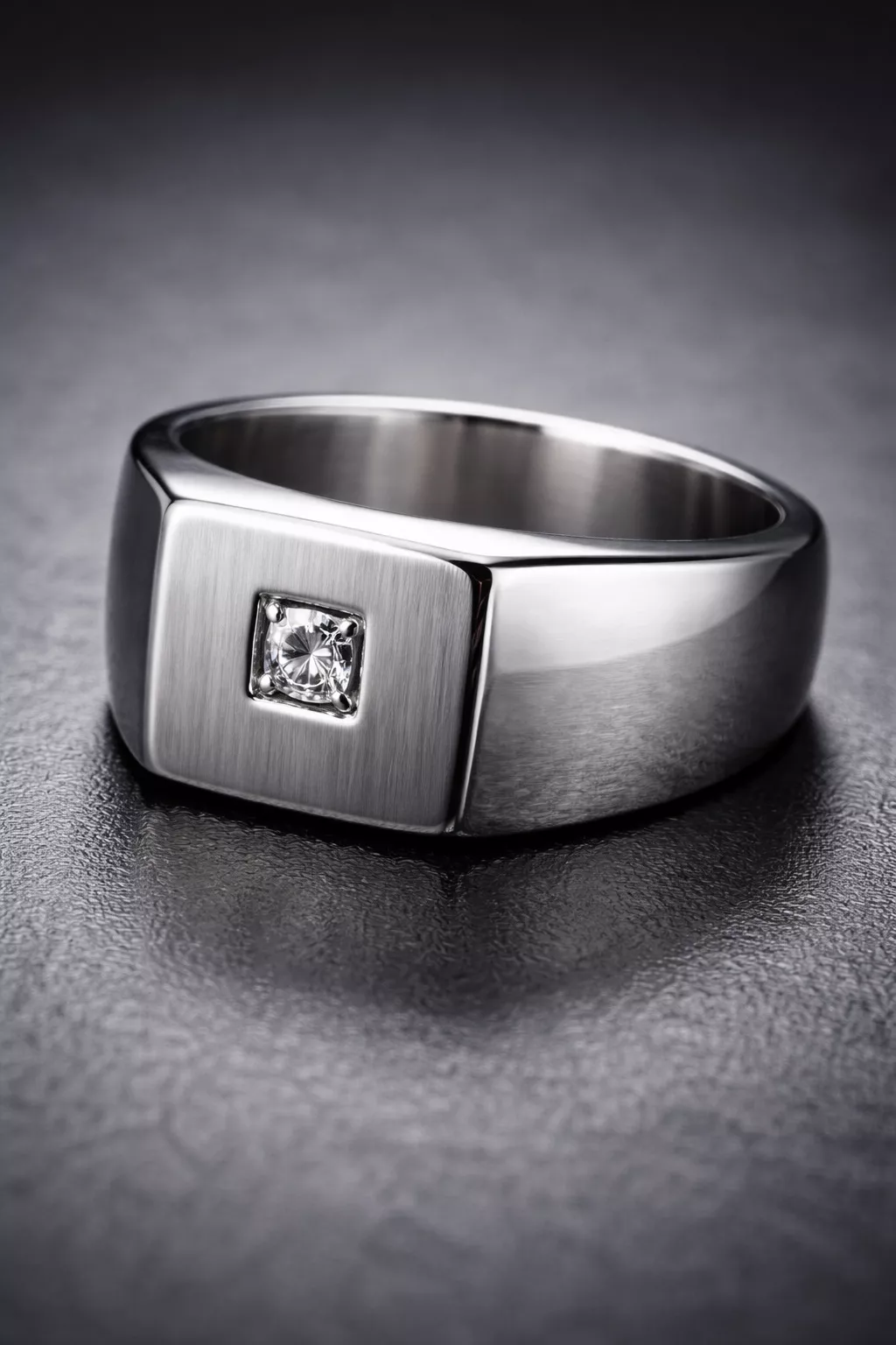 A realistic photo of a heavy silver signet ring with a small square-cut diamond centered on the flat face.