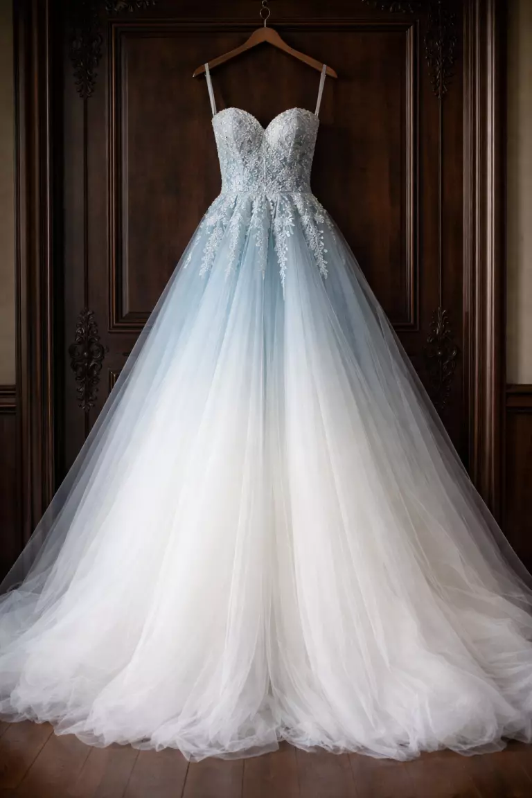 Cool Blue Ombre Wedding Dress A realistic photo of a wedding dress that fades from a cool blue bodice to a crisp white tulle skirt, hanging against a dark wood door.
