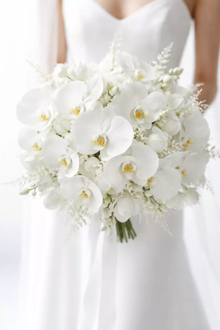 A realistic photo of a wedding bouquet made entirely of white orchids, various textures and sizes, bold minimalist style, bright high key photography.