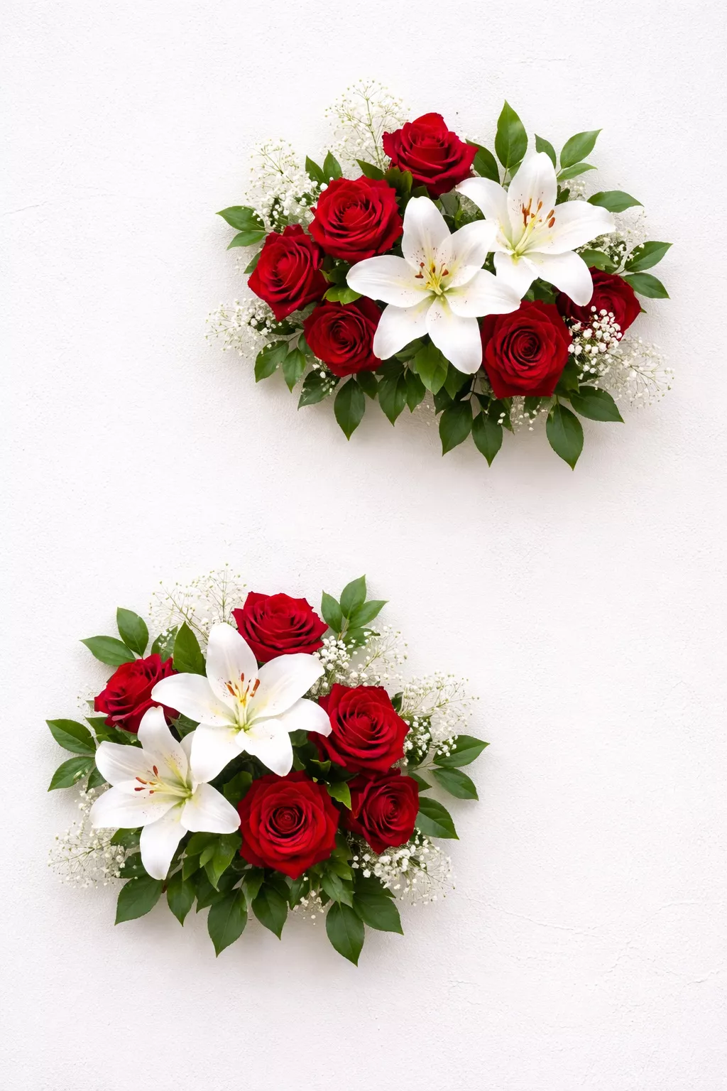 A realistic photo of a white wall with two separate clusters of red roses and white lilies placed at different heights.