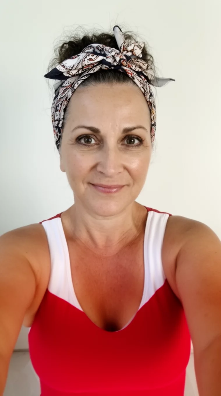 selfie of a 45-year-old woman wearing a red and white swimsuit with a Patterned Scarf hairstyle, front view, minimal background