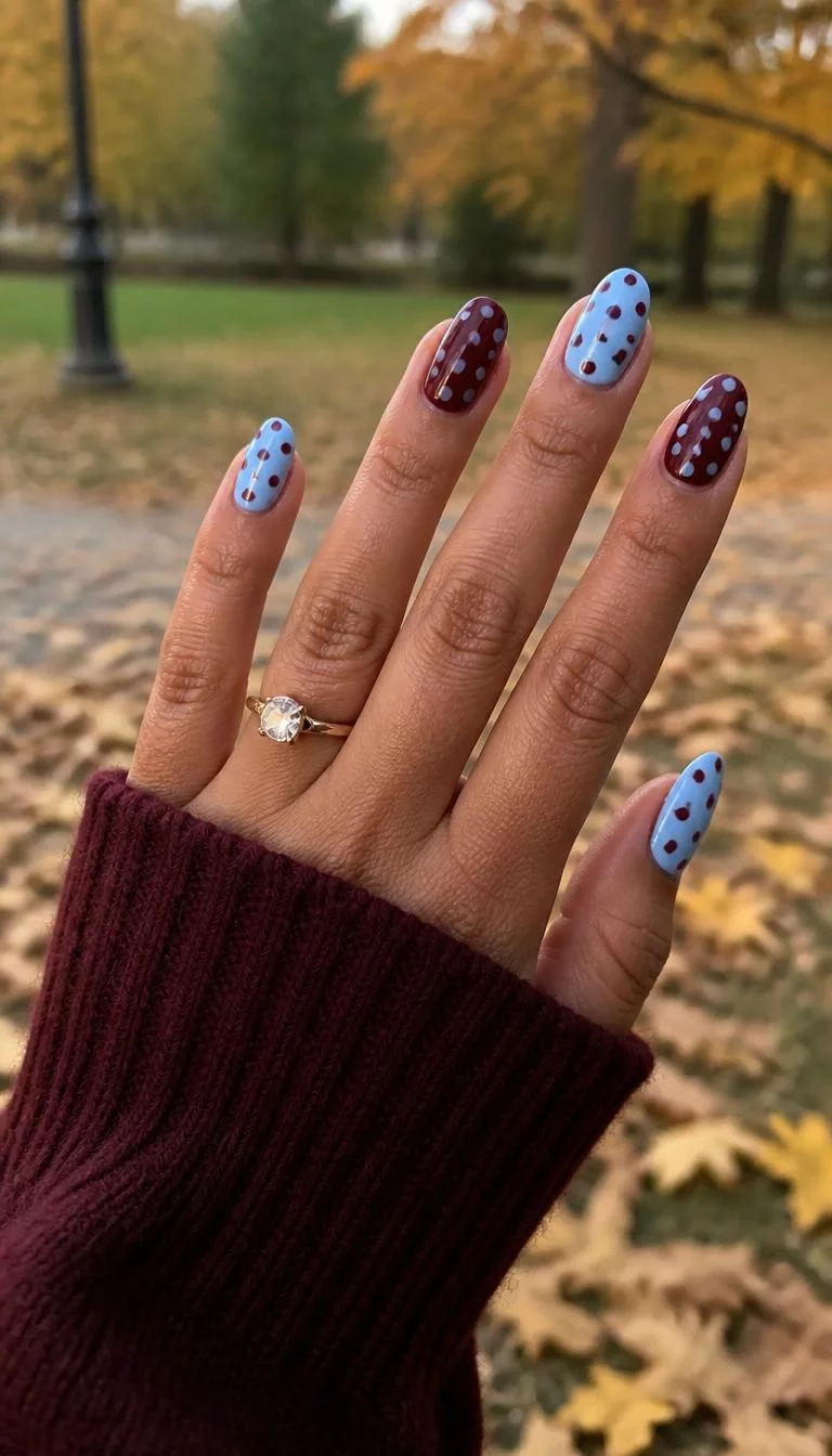 Bold Dots A photorealistic close-up shot of a woman's olive skin tone hand with five fingers, showcasing almond nails medium-length nails featuring bold polka dot patterns in maroon or light blue, outdoor fall background