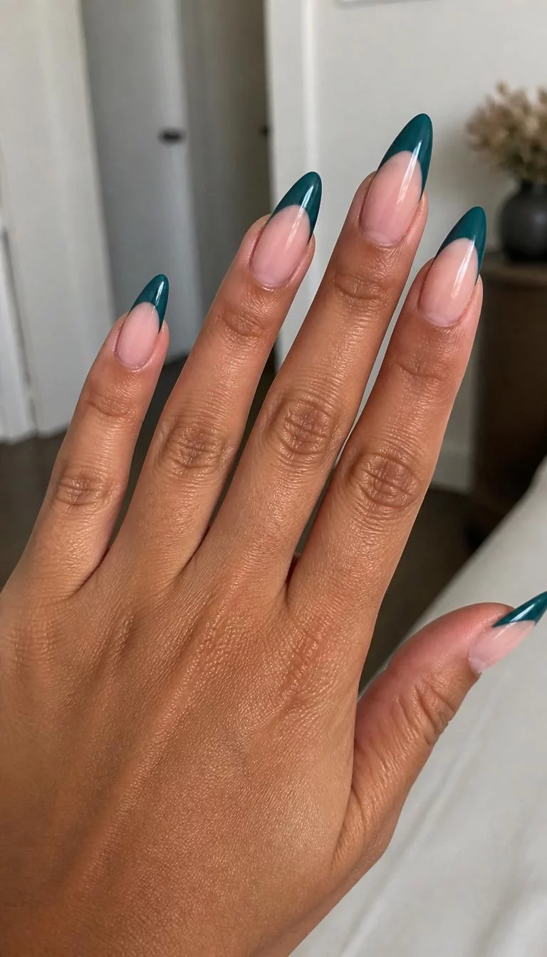 Sophisticated Teal Elegance A photorealistic close-up shot of a woman's tan skin tone hand with five fingers, showcasing stiletto-shaped long nails featuring a classic French tip with a deep teal color, indoor background
