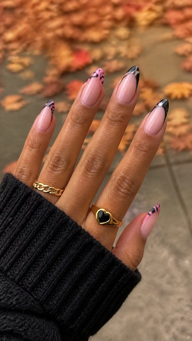 A photorealistic close-up shot of a woman's tan skin tone hand with five fingers, showcasing stiletto-shaped medium-length nails featuring a French tip design and a pink and black pattern, outdoor fall background