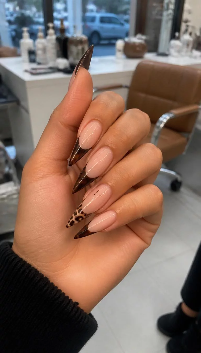 A photorealistic close-up shot of a woman's olive skin tone hand with five fingers, showcasing long stiletto-shaped nails featuring french tips with dark brown polish and intricate designs like animal print and swirls, nail salon background