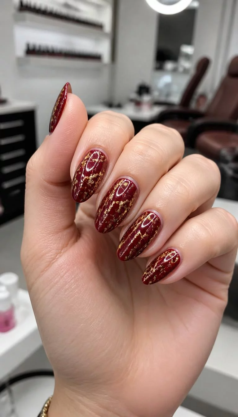 A photorealistic close-up shot of a woman's light skin tone hand with five fingers, showcasing almond-shaped medium-length nails featuring a deep red color and a striking gold crackle design, nail salon background