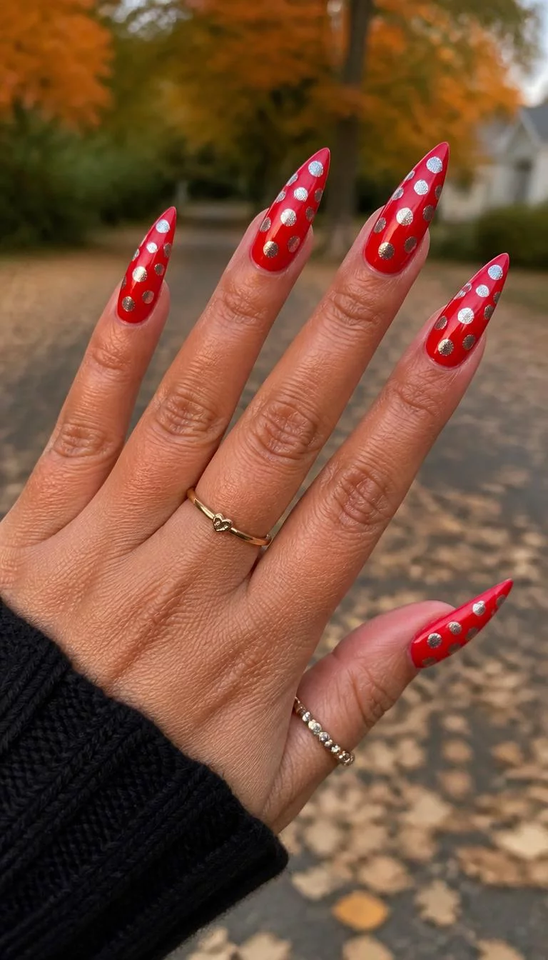 Silver Polka Dot Stiletto Drama A photorealistic close-up shot of a woman's tan skin tone hand with five fingers, showcasing stiletto long nails featuring a vibrant red, decorated with an intricate pattern of metallic silver polka dots, outdoor fall background